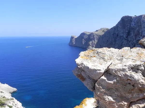Steile Felsküste am Cap Formentor auf Mallorca mit tiefblauem Mittelmeer und Leuchtturm in der Ferne.