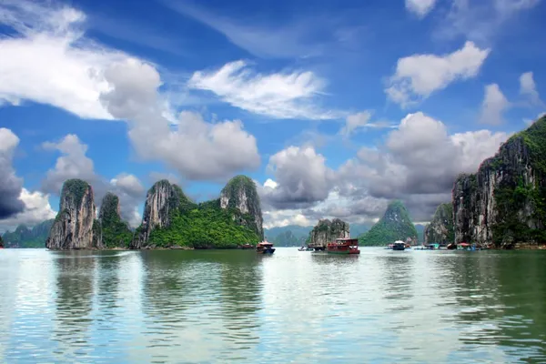 Dschunken zwischen bewachsenen Kalksteinfelsen in der Halong-Bucht in Vietnam.